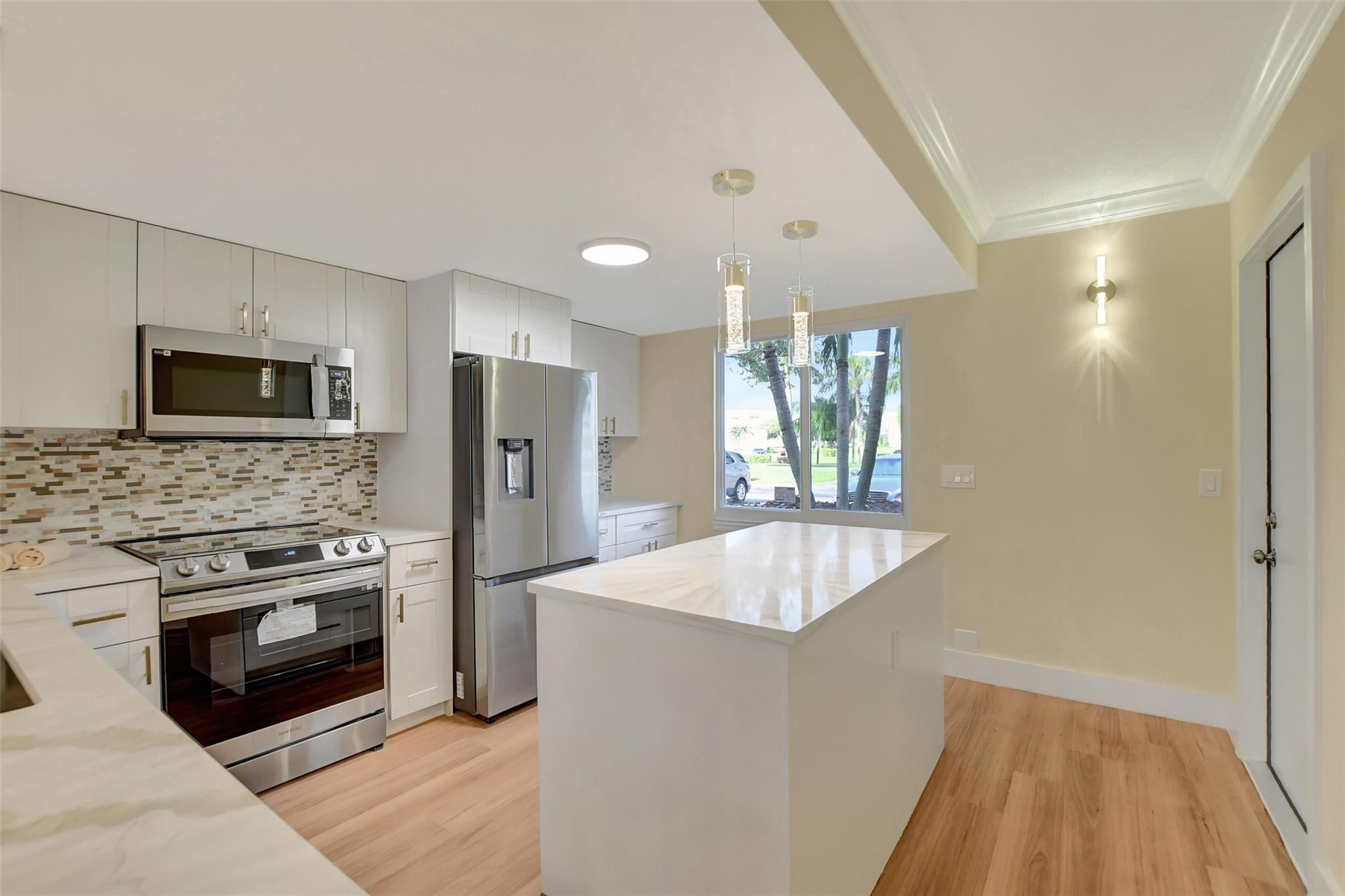 1019 Guildford East, Unit 1019 Boca Raton, FL 33434 - Photo 12 of 38 a kitchen with kitchen island a sink appliances and cabinets