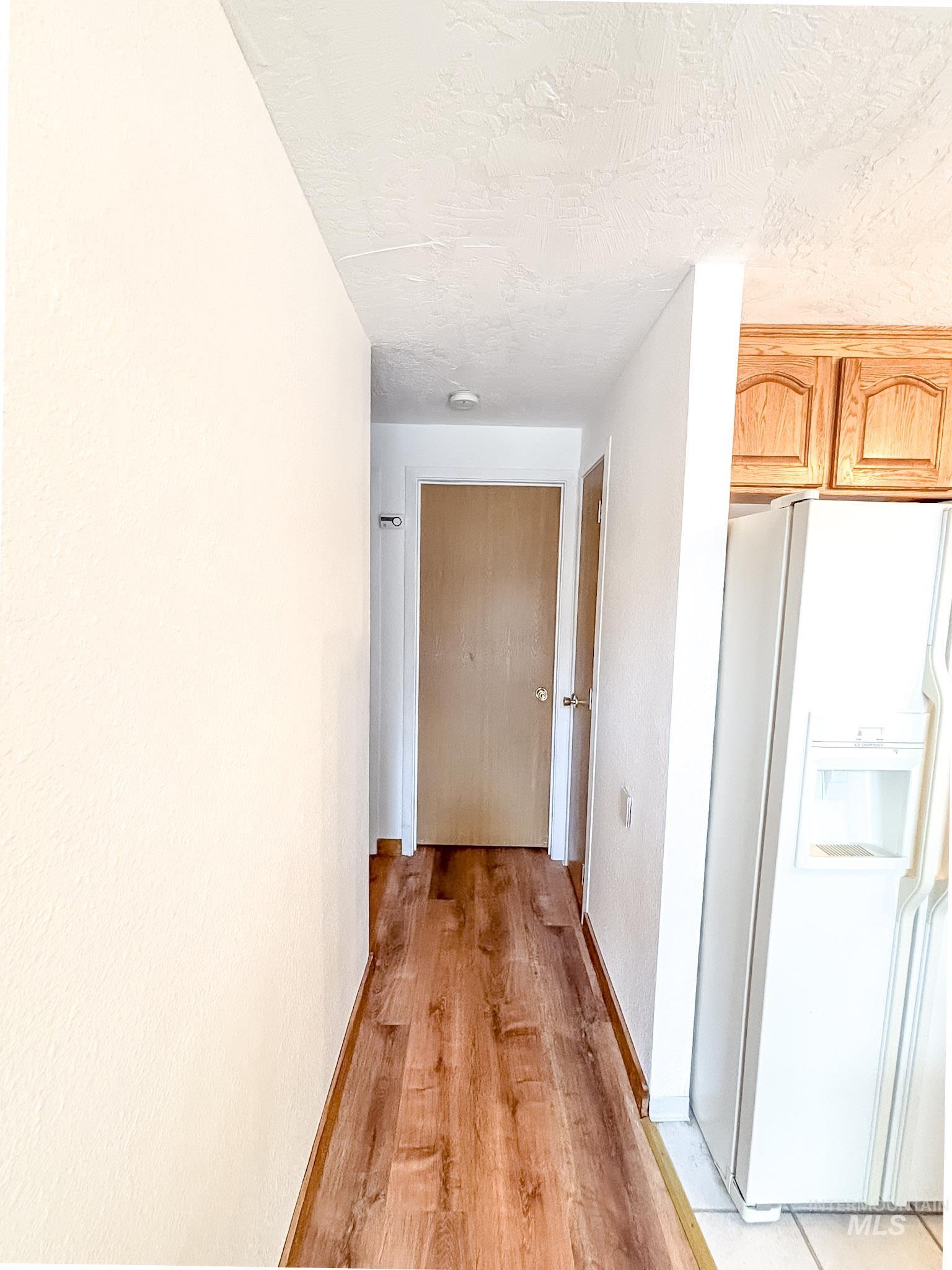 302 Rossiter Court Pierce, ID 83546 - Photo 11 of 30 Hallway featuring wood-finish flooring, white painted walls, and a ceiling-mounted light fixture