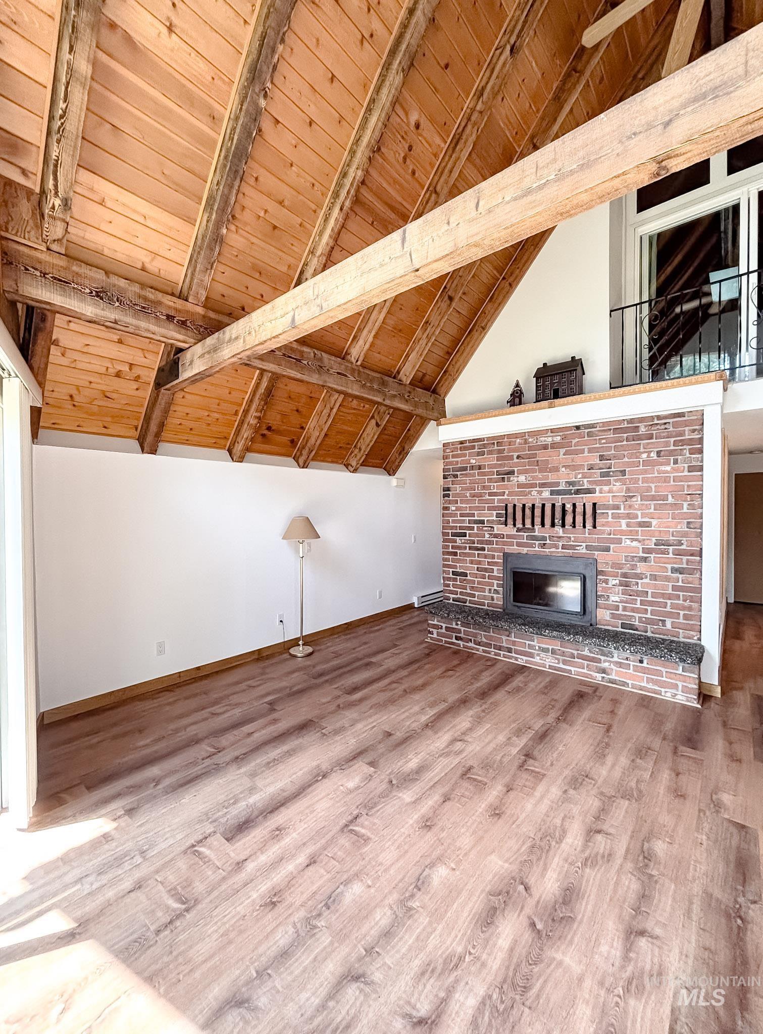 302 Rossiter Court Pierce, ID 83546 - Photo 18 of 30 Vaulted wood-plank ceiling with exposed beams, brick fireplace with a stone-finish hearth, and wood-finish flooring