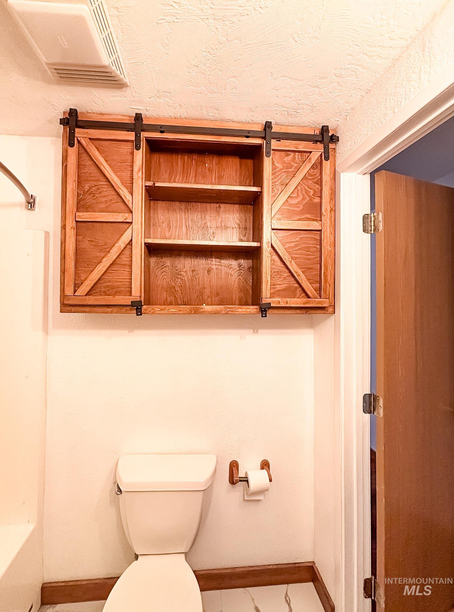 302 Rossiter Court Pierce, ID 83546 - Photo 21 of 30 Wood-finish barn door style cabinetry with open shelving