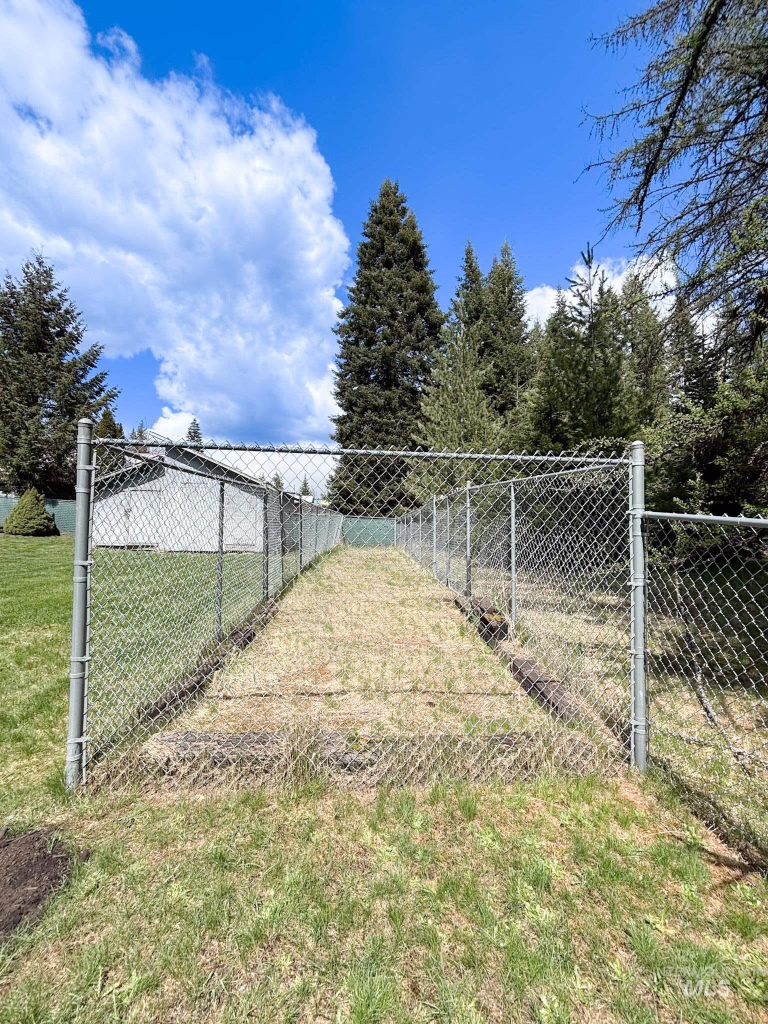 302 Rossiter Court Pierce, ID 83546 - Photo 28 of 30 Fenced outdoor area featuring a chain-link enclosure, established evergreens, and natural ground cover