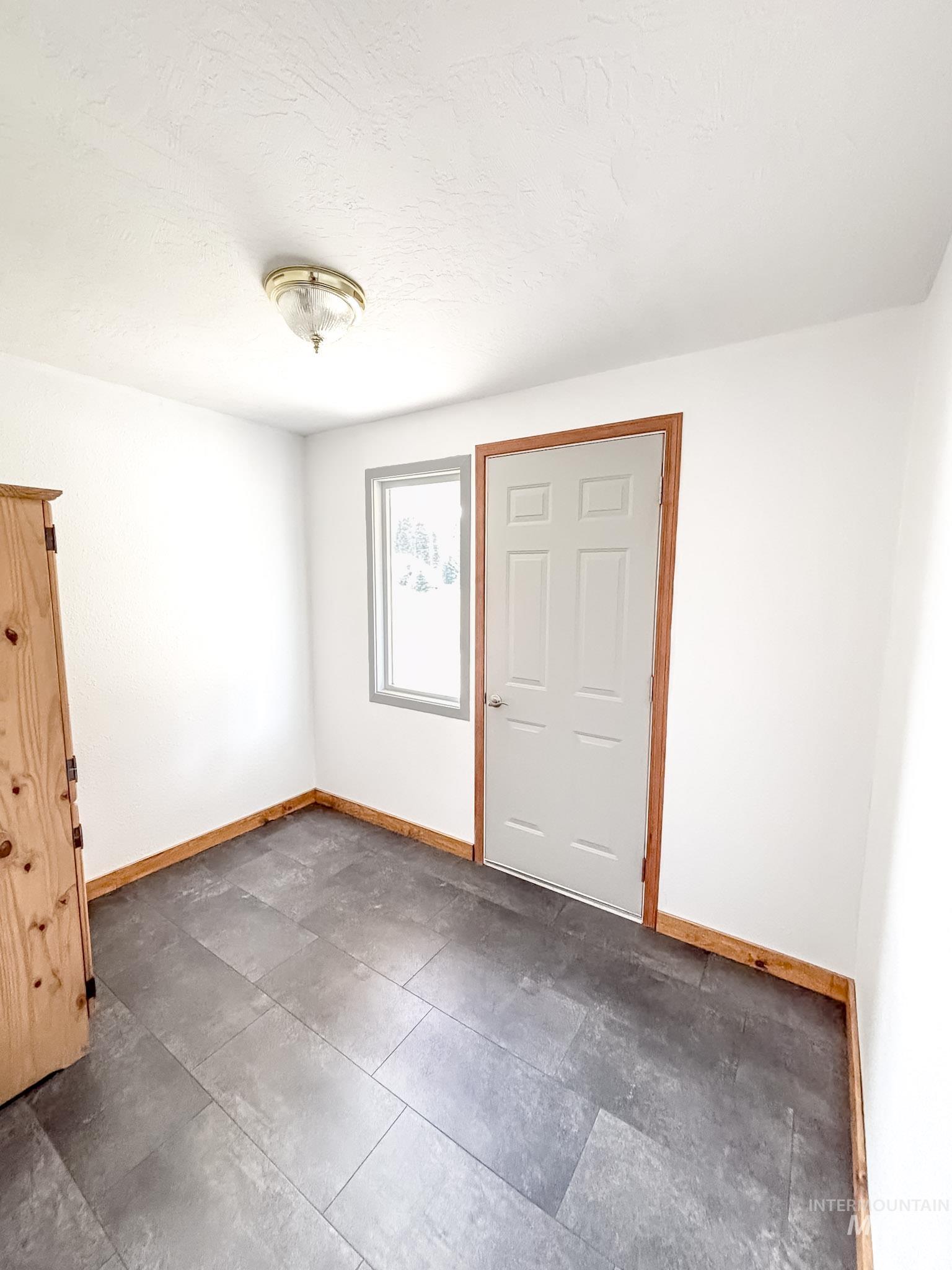 302 Rossiter Court Pierce, ID 83546 - Photo 6 of 30 Room featuring dark-toned plank flooring, white walls, and a multi-panel door with natural wood trim