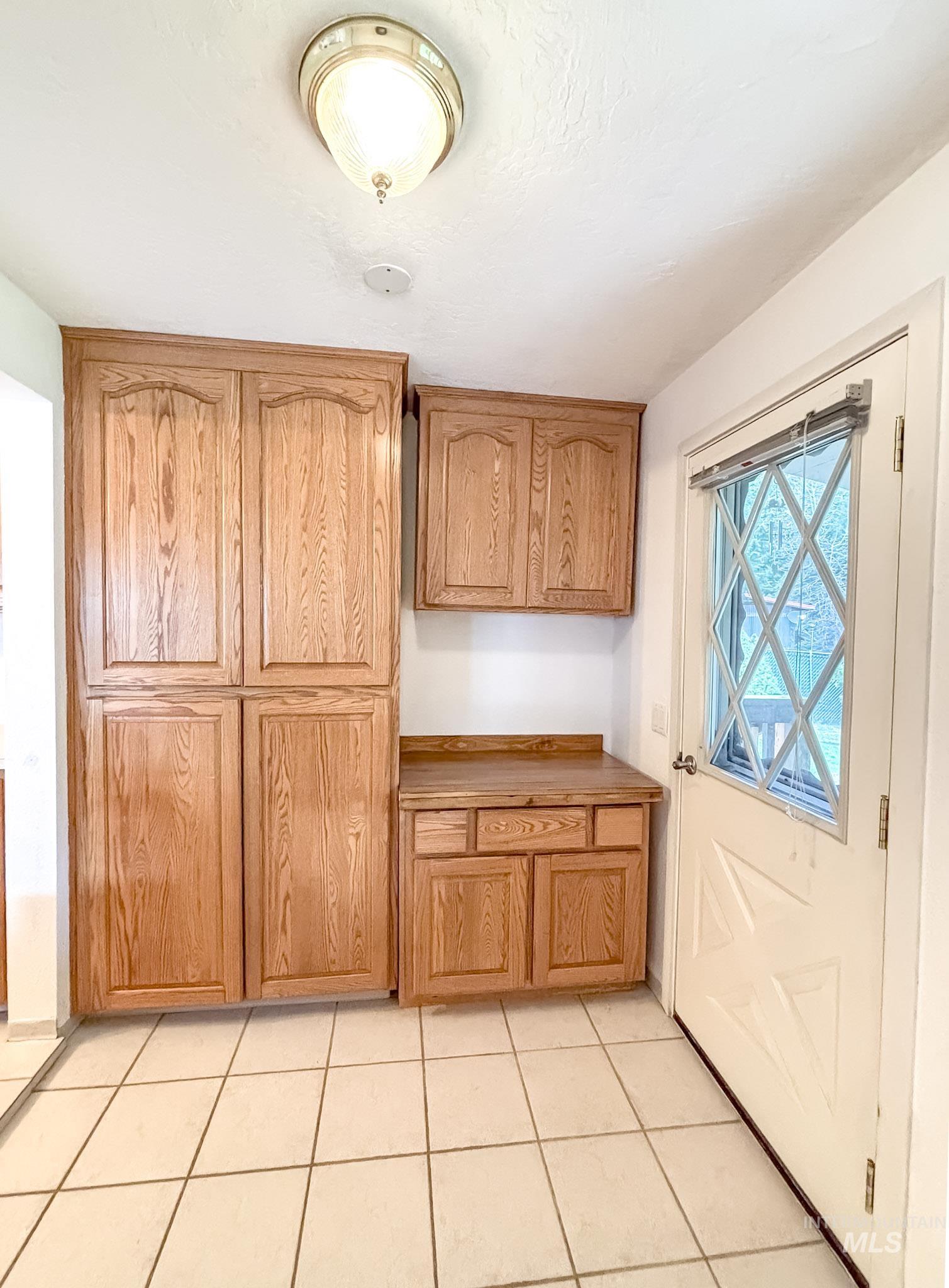 302 Rossiter Court Pierce, ID 83546 - Photo 7 of 30 Kitchen area featuring tile flooring, wooden cabinetry, and a door with an integrated window