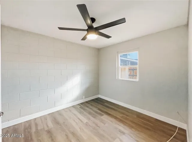 an empty room with wooden floor and ceiling fan