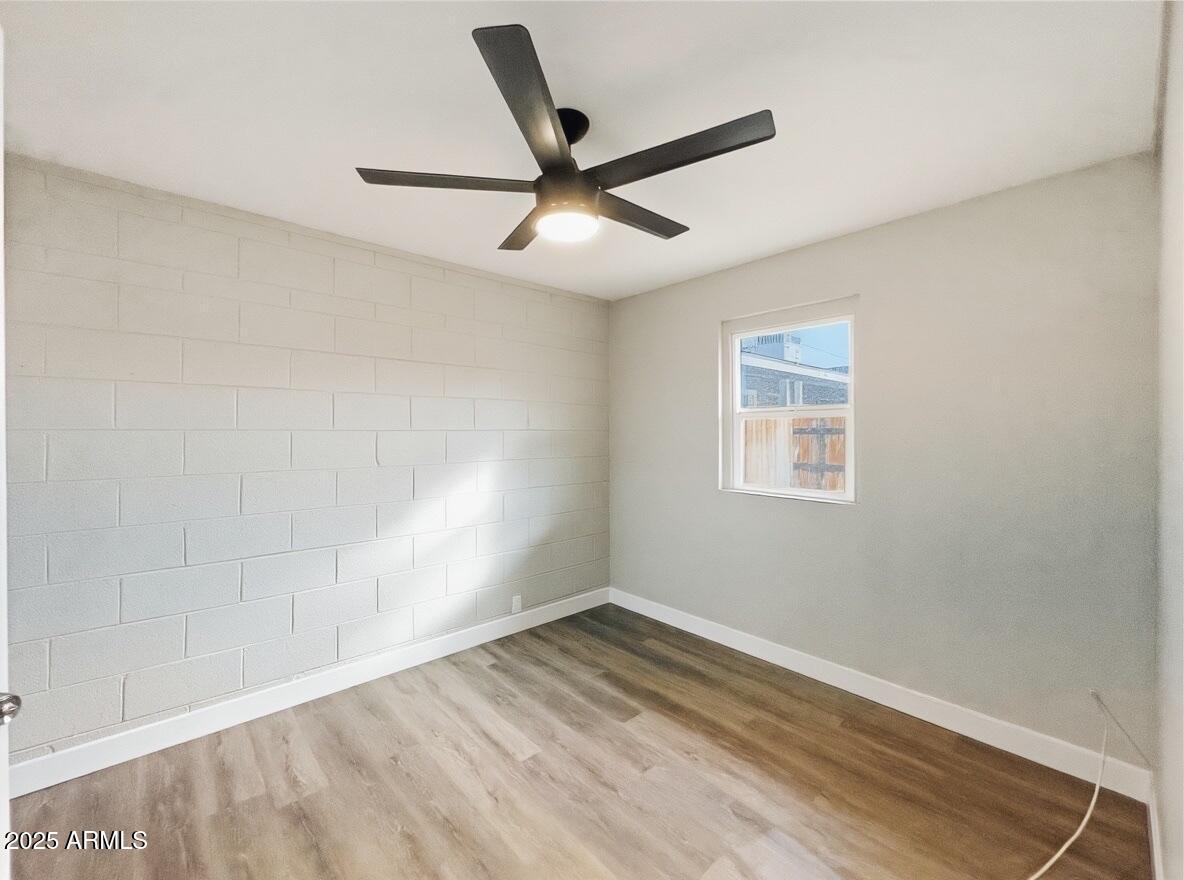 513 East Hatcher Road, Unit 6 Phoenix, AZ 85020 - Photo 6 of 8 an empty room with wooden floor and ceiling fan