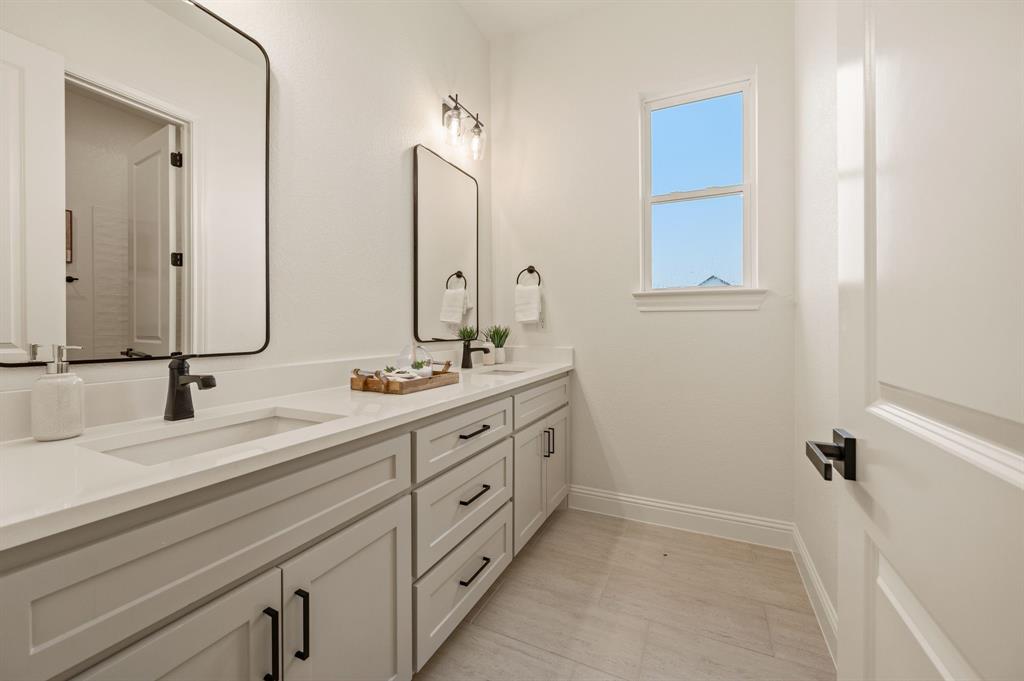 3006 Wheeler Branch Road Granbury, TX 76049 - Photo 26 of 29 Dual vanity with light gray cabinetry, integrated sinks, black fixtures, and framed mirrors