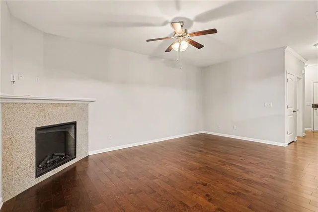 an empty room with wooden floor fan and windows