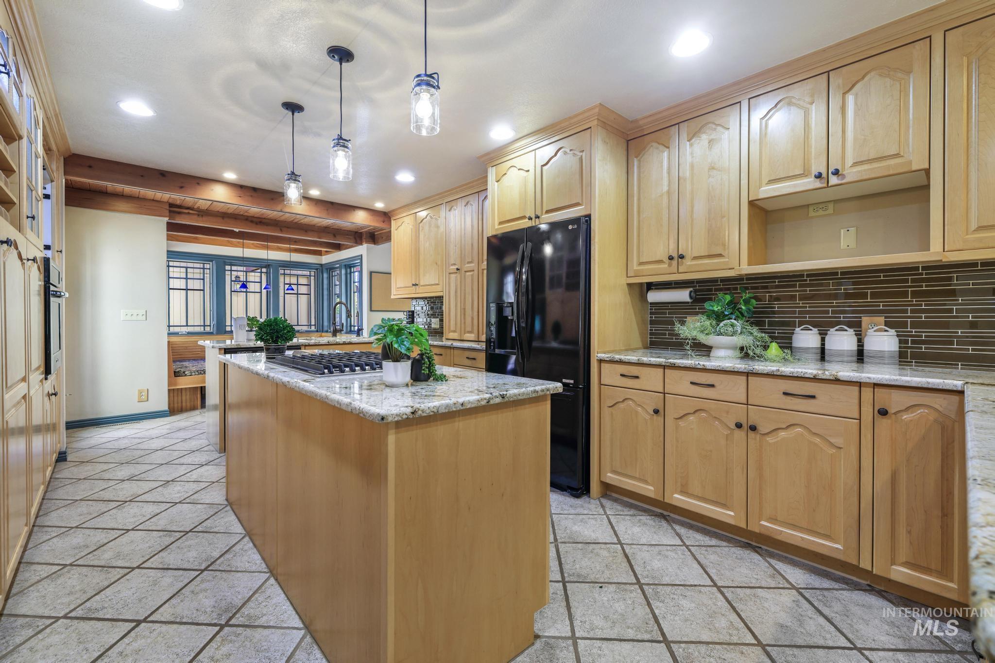 1172 Hankins Road North Twin Falls, ID 83301 - Photo 15 of 49 Kitchen featuring a kitchen island, light stone countertops, stainless steel appliances, beam ceiling, and decorative light fixtures
