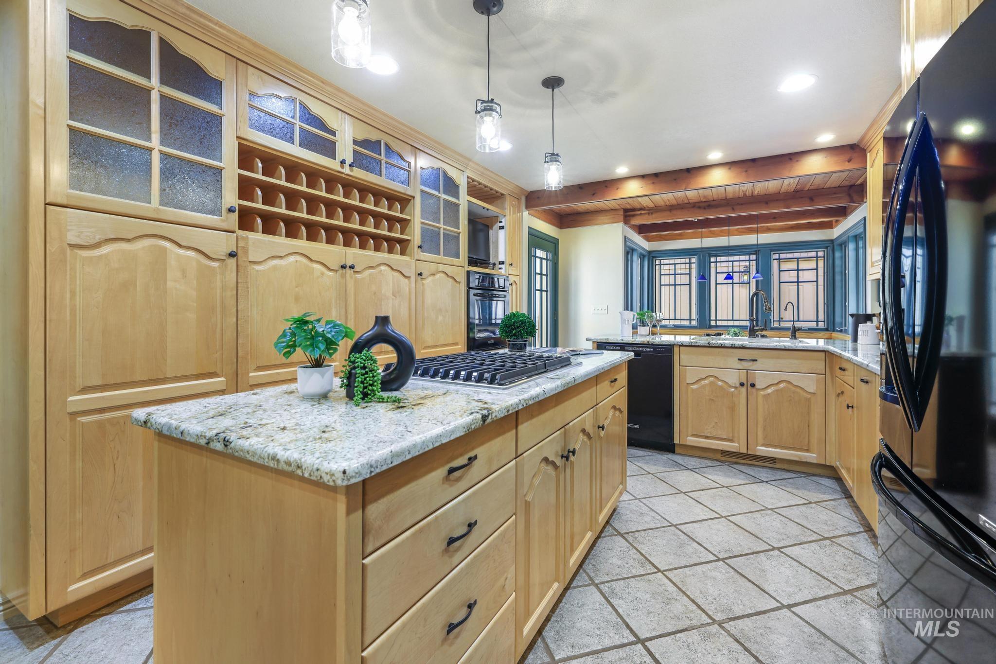 1172 Hankins Road North Twin Falls, ID 83301 - Photo 16 of 49 Kitchen with glass fronted cabinets, black appliances, light stone counters, light wood finish cabinetry, and hanging light fixtures