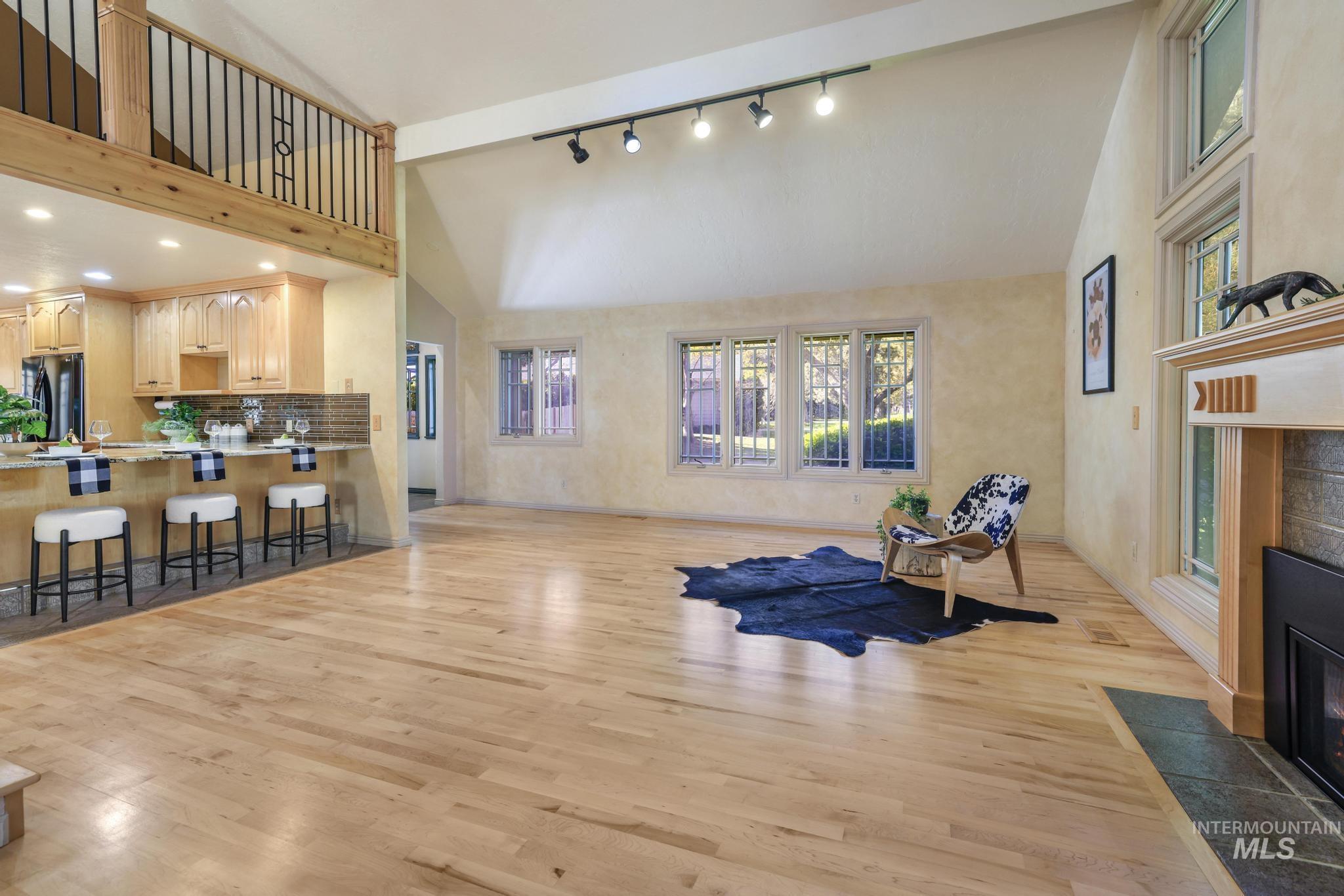 1172 Hankins Road North Twin Falls, ID 83301 - Photo 24 of 49 Exercise area featuring a tiled fireplace, vaulted ceiling, light wood-type flooring, and track lighting