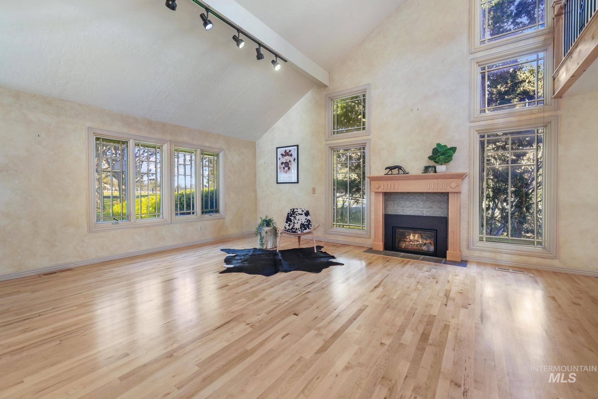 1172 Hankins Road North Twin Falls, ID 83301 - Photo 26 of 49 Exercise area with vaulted ceiling, rail lighting, light wood-type flooring, and a fireplace with flush hearth
