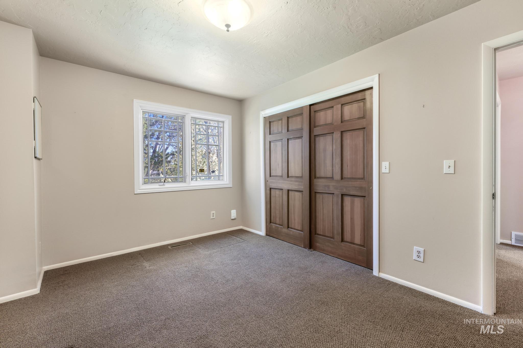1172 Hankins Road North Twin Falls, ID 83301 - Photo 31 of 49 Unfurnished bedroom featuring dark carpet, a closet, and a textured ceiling