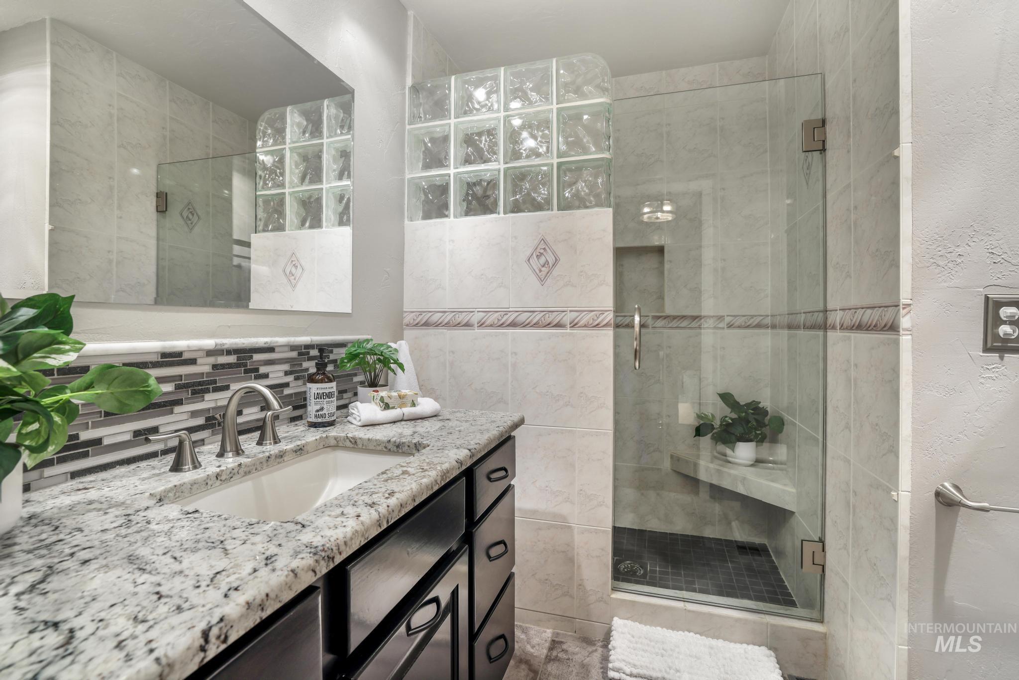 1172 Hankins Road North Twin Falls, ID 83301 - Photo 33 of 49 Bathroom featuring a shower stall, vanity, and decorative backsplash