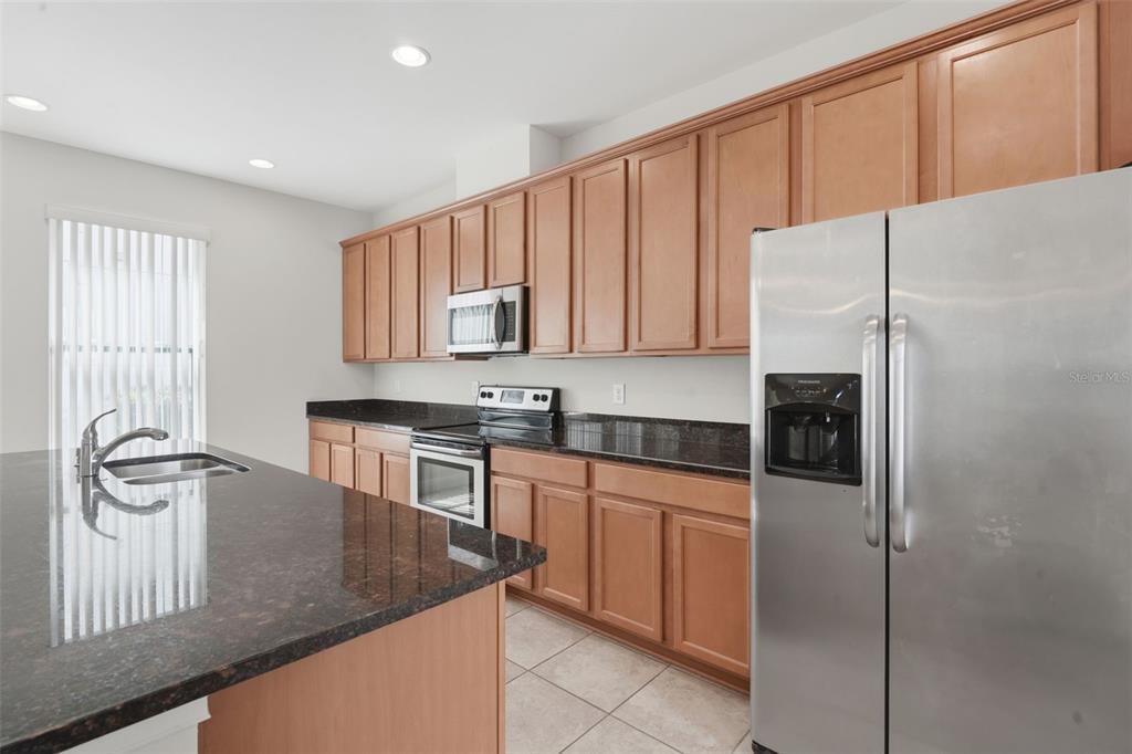 11486 Misty Oak Alley Windermere, FL 34786 - Photo 20 of 47 a kitchen with stainless steel appliances granite countertop a refrigerator a stove and a sink with wooden cabinets
