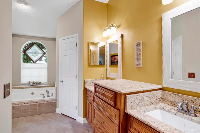 a bathroom with a granite countertop tub a double vanity sink and a mirror
