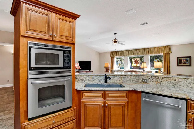 a kitchen with granite countertop a sink stove and cabinets