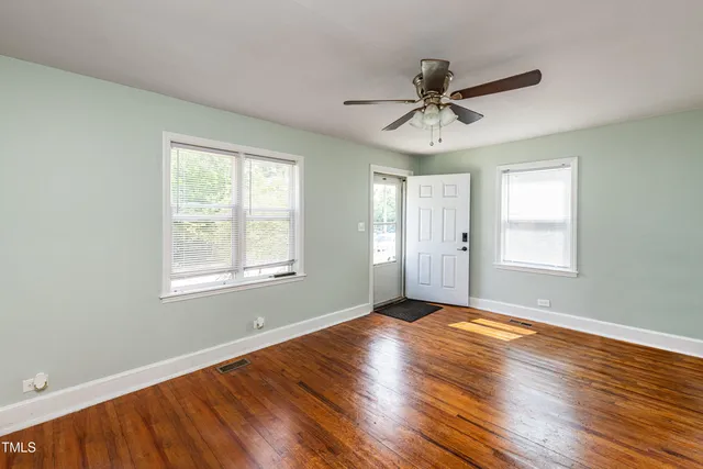 a view of an empty room with wooden floor and a window
