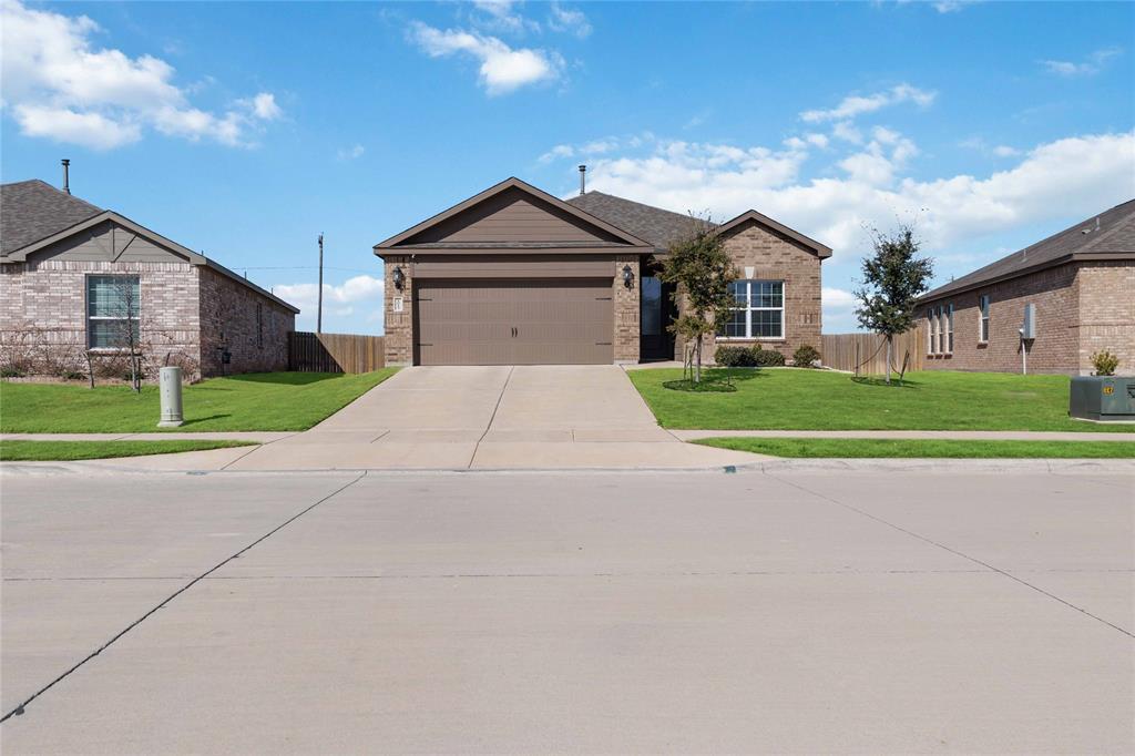 1012 Calhoun Drive Anna, TX 75409 - Photo 1 of 39 Brick and siding exterior featuring an attached two-car garage, concrete driveway, and front lawn with young trees