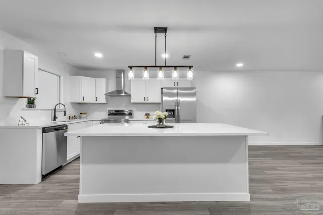 a kitchen with kitchen island stainless steel appliances a sink a stove a center island and cabinets