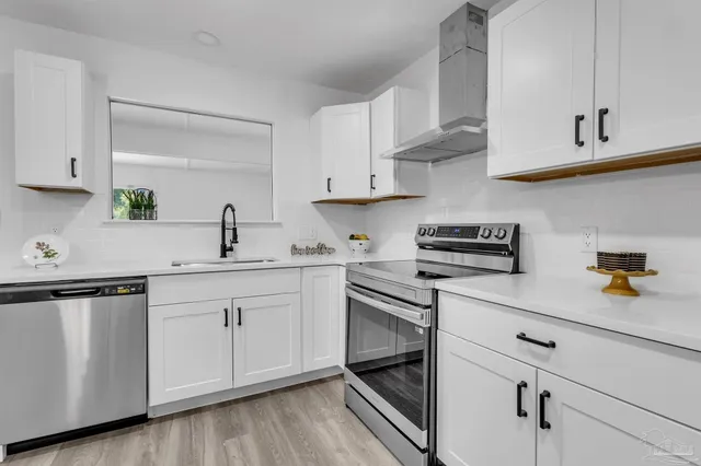 a kitchen with white cabinets stainless steel appliances and sink