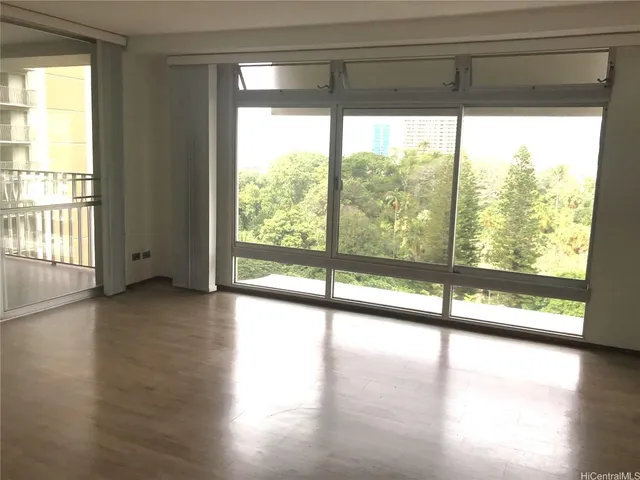 a view of an empty room with wooden floor and a window