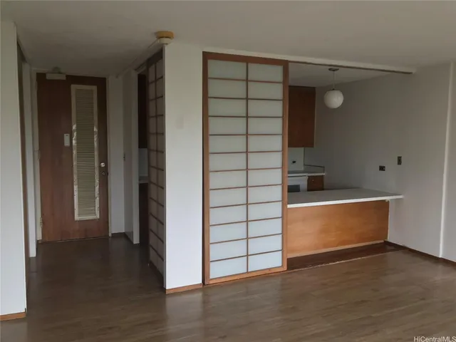 a view of an empty room with wooden floor and cabinet