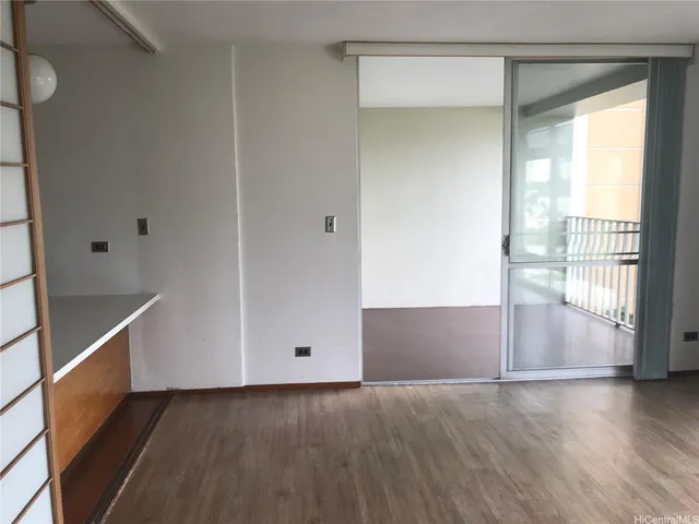 a view of an empty room with wooden floor and a window