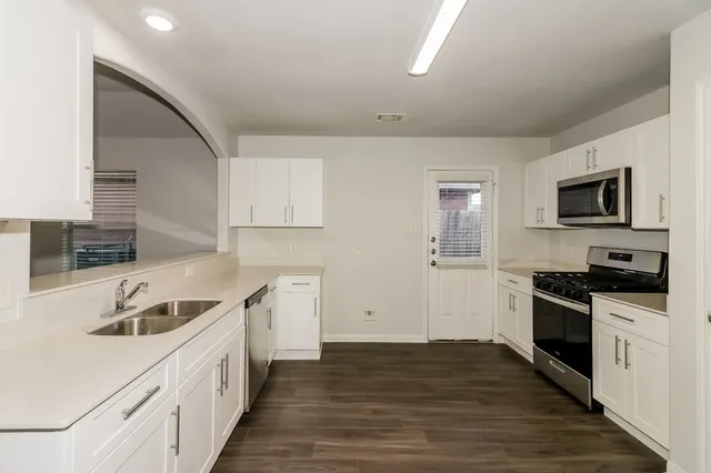 a kitchen with a sink stove top oven and cabinets