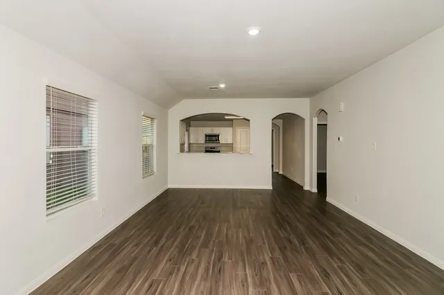 an empty room with wooden floor and windows
