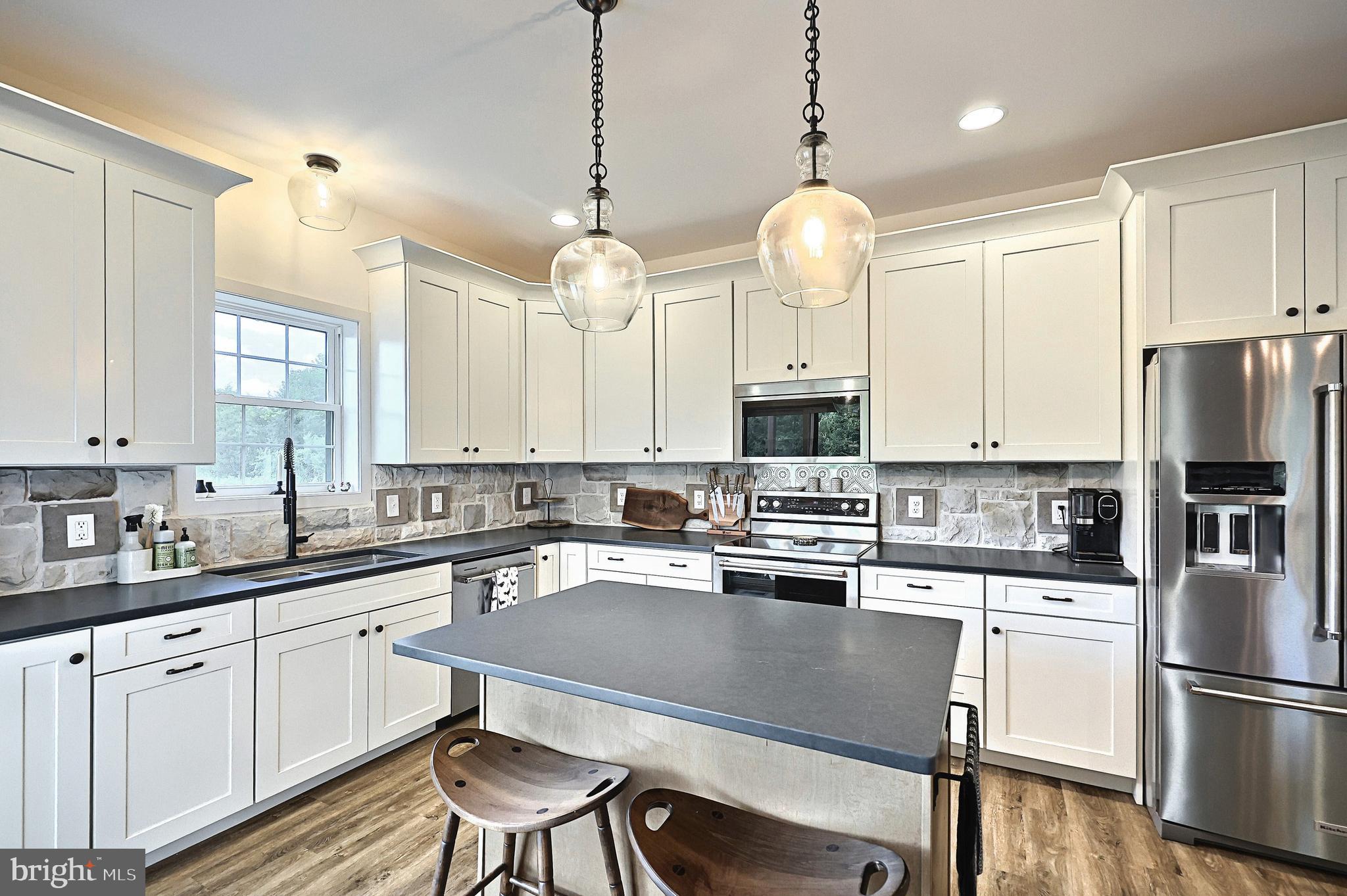 4575 Lewisberry Road York, PA 17404 - Photo 24 of 56 a kitchen with stainless steel appliances granite countertop a stove a refrigerator a sink dishwasher a dining table and chairs with wooden floor