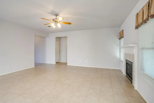 a view of a livingroom with a fireplace a ceiling fan and windows