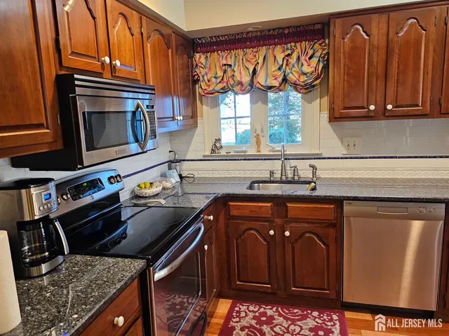 a kitchen with stainless steel appliances granite countertop a stove a sink and a microwave