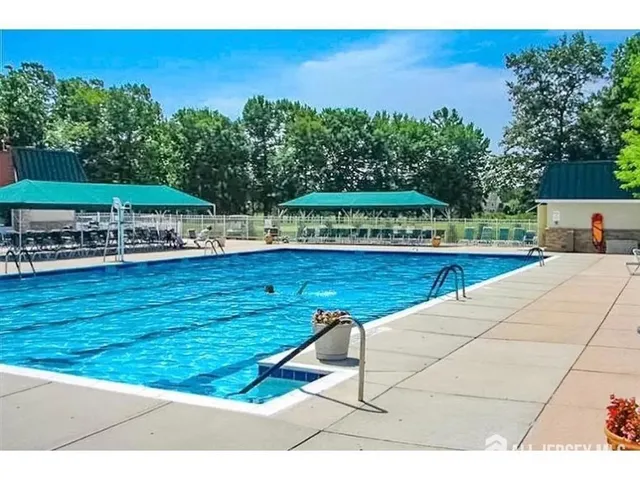 a view of a swimming pool with lawn chairs under an umbrella
