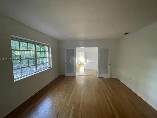 an empty room with wooden floor and windows
