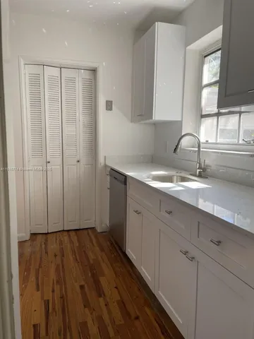 a view of a kitchen with wooden floor and cabinets