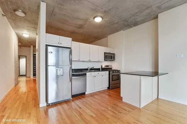 a kitchen with stainless steel appliances a refrigerator and wooden floor