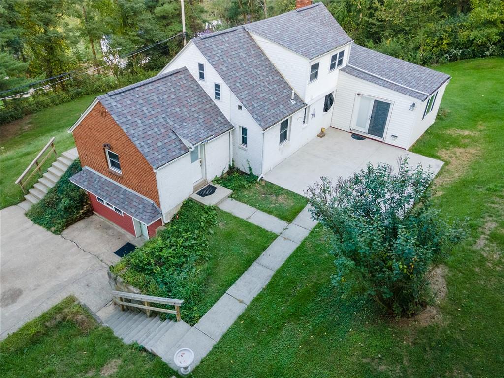 a aerial view of a house with a yard plants and large tree