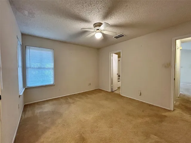 an empty room with windows and fan
