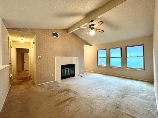 an empty room with windows and fireplace
