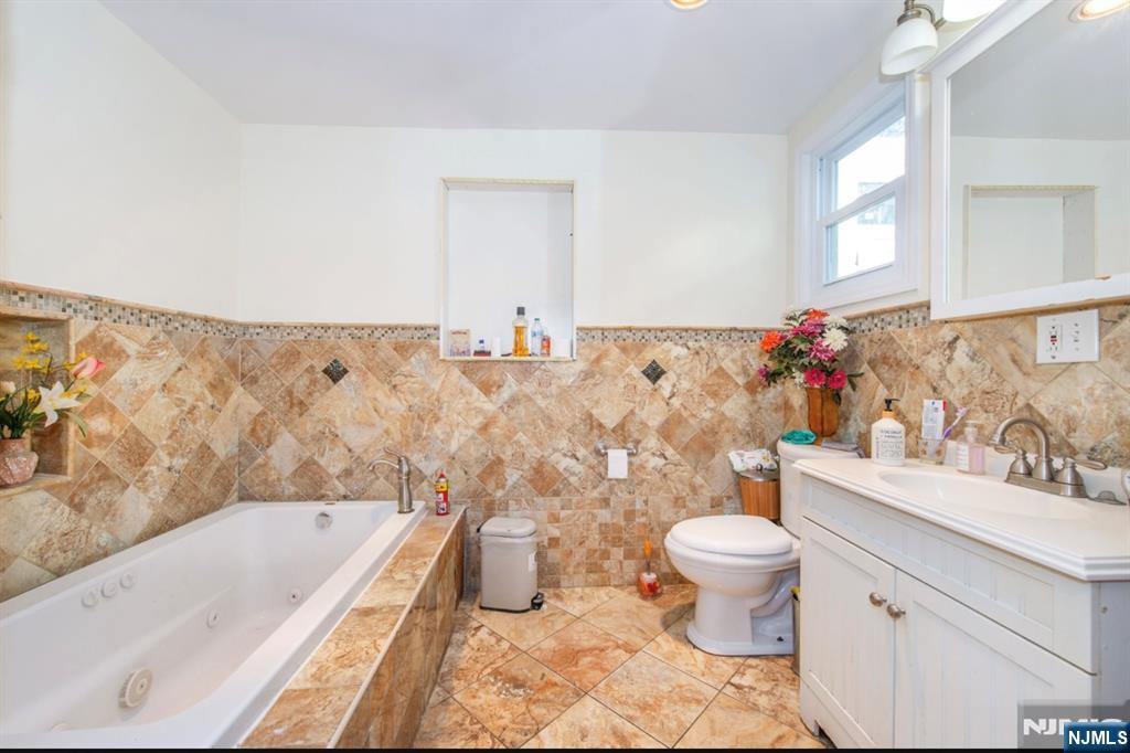 337-379 Ellison Street Paterson, NJ 07501 - Photo 19 of 27 a bathroom with a sink toilet mirror vanity and bathtub
