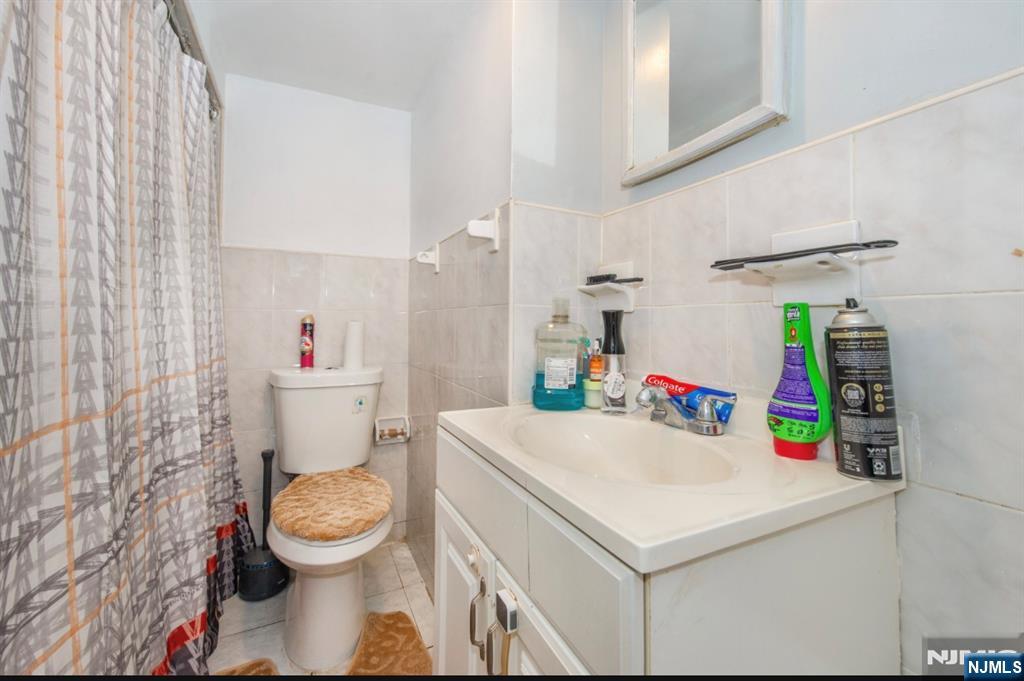 337-379 Ellison Street Paterson, NJ 07501 - Photo 26 of 27 a bathroom with a sink a toilet and a shower curtain