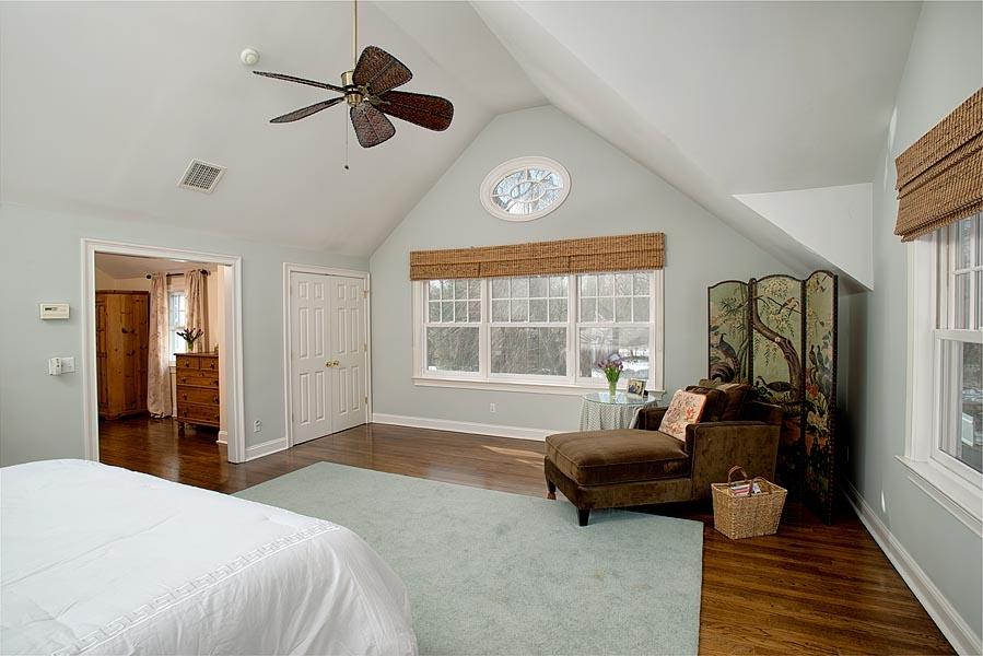 82 Parish Road New Canaan, CT 06840 - Photo 17 of 22 a spacious bedroom with a bed a couch and a chandelier