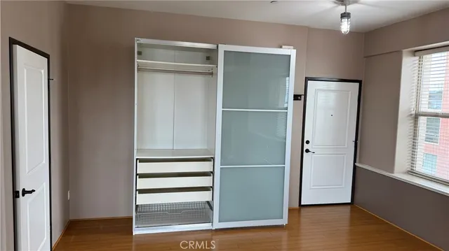 a view of walk in closet with wooden floor and cabinet