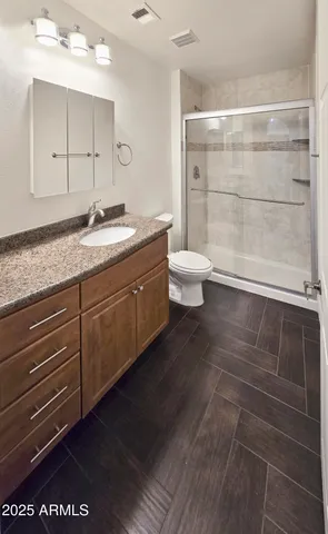 a bathroom with a granite countertop sink a toilet and a shower