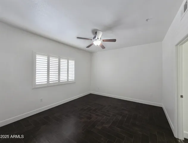 an empty room with a window and a ceiling fan