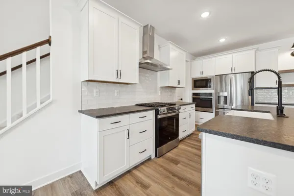 a kitchen with stainless steel appliances granite countertop a stove a sink dishwasher and a refrigerator with wooden floors