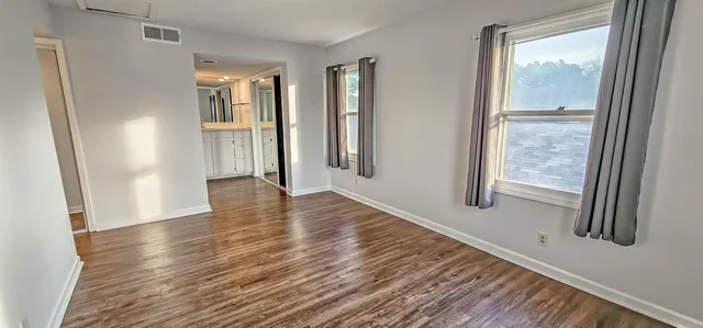 a view of an empty room with wooden floor and a window