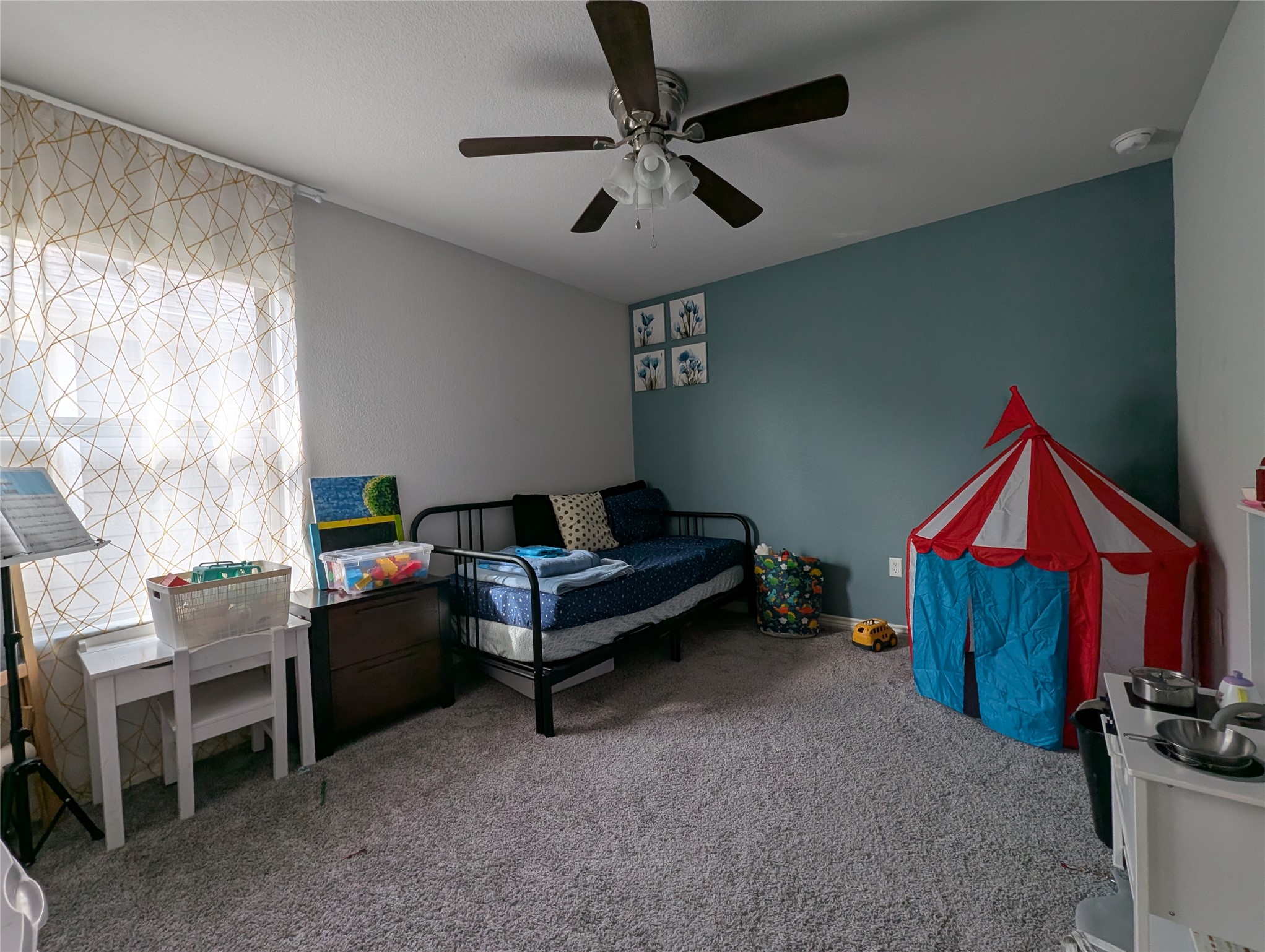14502 McCoy Loop Austin, TX 78717 - Photo 14 of 26 Carpeted room featuring a ceiling fan with integrated lighting, a window with sheer patterned curtains, and an accent wall