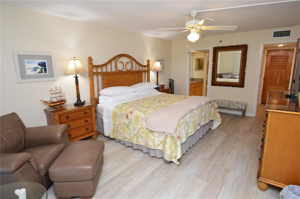 900 Gulf Boulevard, Unit 907 Indian Rocks Beach, FL 33785 - Photo 39 of 88 a bedroom with a bed a mirror on dresser and a chandelier