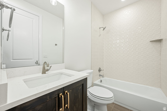 684 West High Tide Place, Unit 131 St. George, UT 84790 - Photo 12 of 27 Bathroom featuring a vanity with a white countertop and rectangular undermount sink, dark wood-finish cabinetry with brass-tone hardware, a full-width mirror, and a tub-shower combination with textured white wall tile and an integrated niche